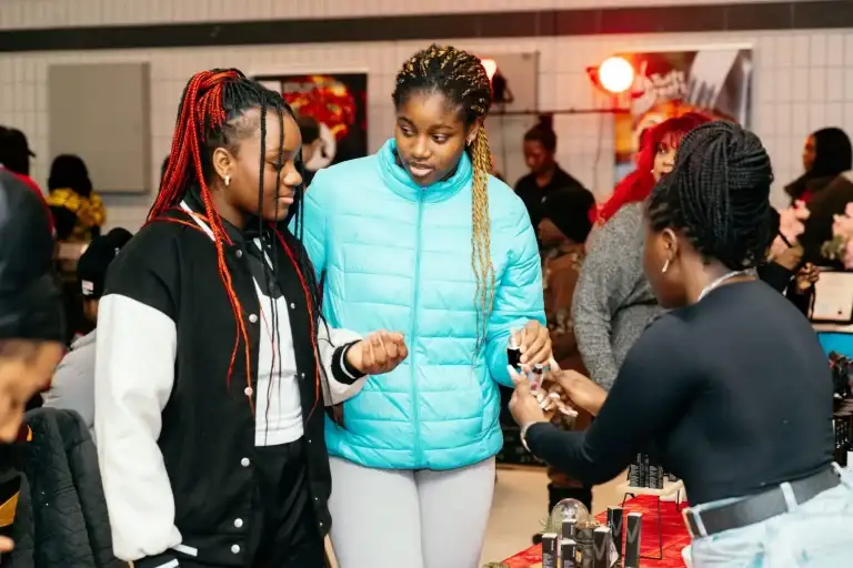 Young people browsing a Black-owned beauty stall at the community vendor market